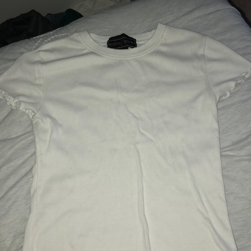 white tee with ruffles on the bottom and arms